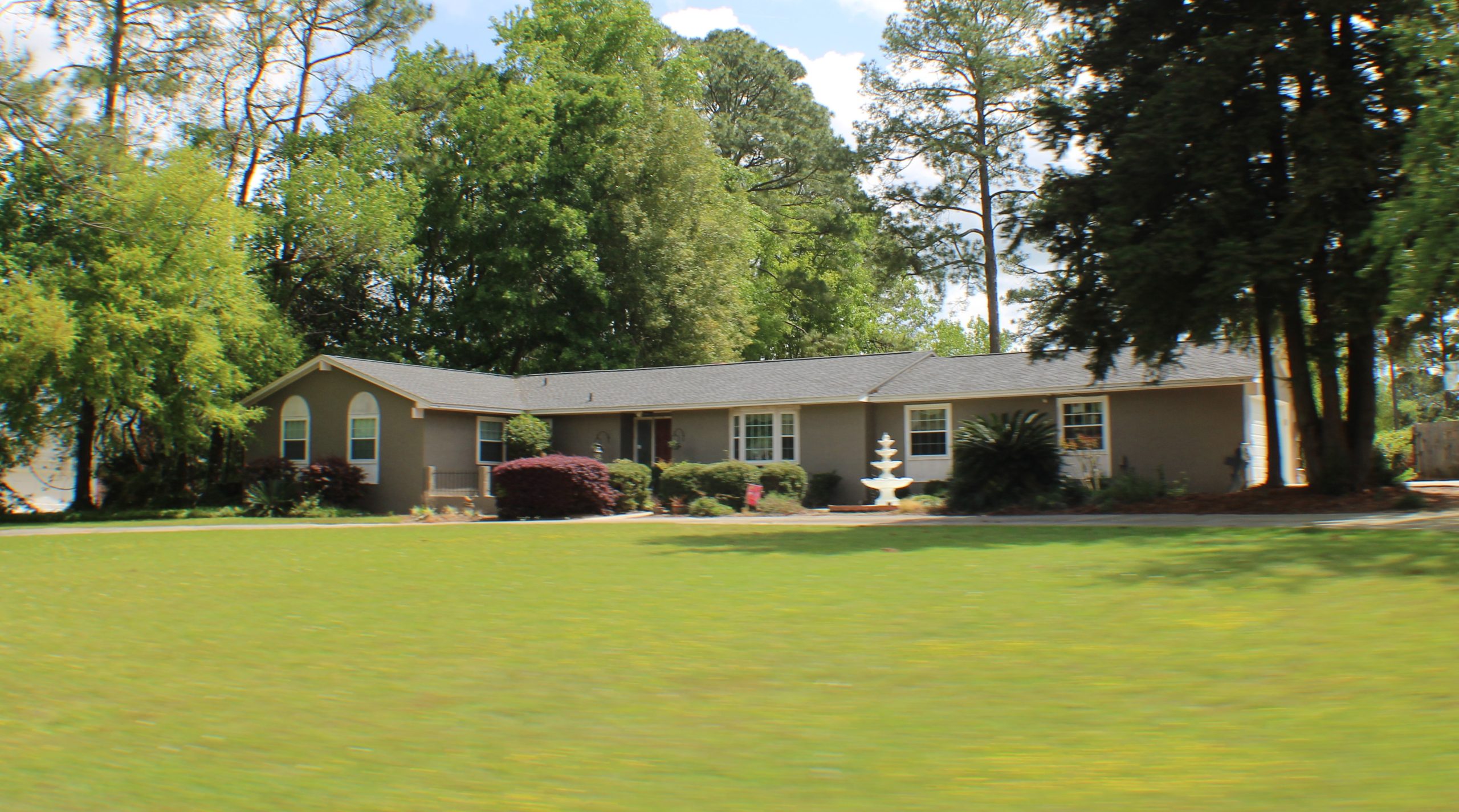 Brick ranch home with a large front yard and white fountain found in Killearn Tallahassee
