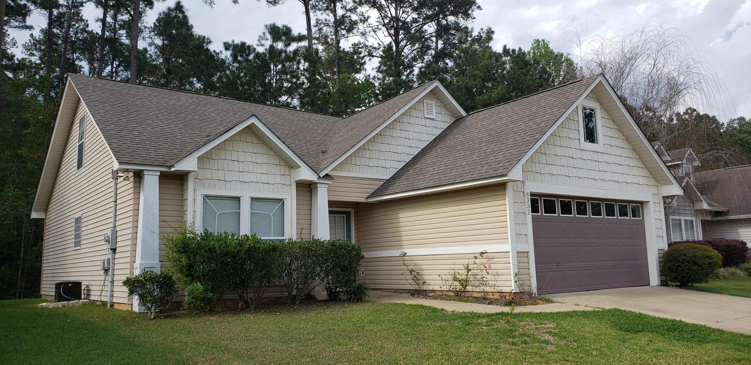 Picture is decorative. This is a typical home tour for Tallahassee. It shows the front of the home with a recessed door in the middle of a two car garge and double windows. There are shrubs in front of the window.